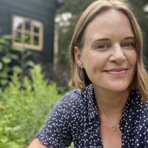 closeup photo of woman with garden behind her