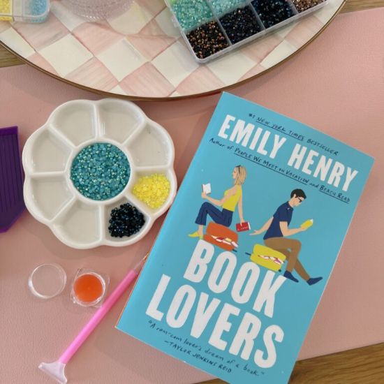 a partitioned tray containing colored beads, alongside a paperback book titled Book Lovers