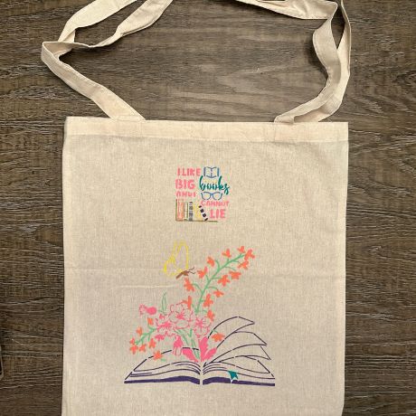 Tote bag with stencil graphic of a book opened flat and flowers rising from it