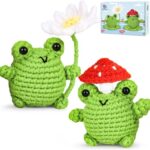 two crochet green frogs, one holding white daisy, the other with toadstool on head