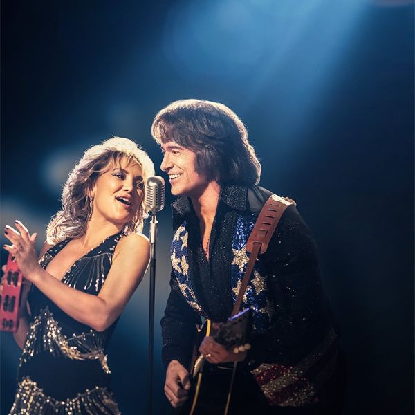 man on woman on stage singing into a microphone