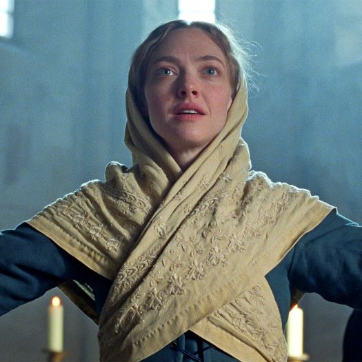 Woman with blue dress and tan shawl, standing with arms outstretched