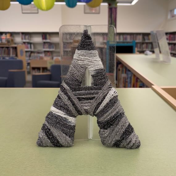 The letter A wrapped in grey yarn
