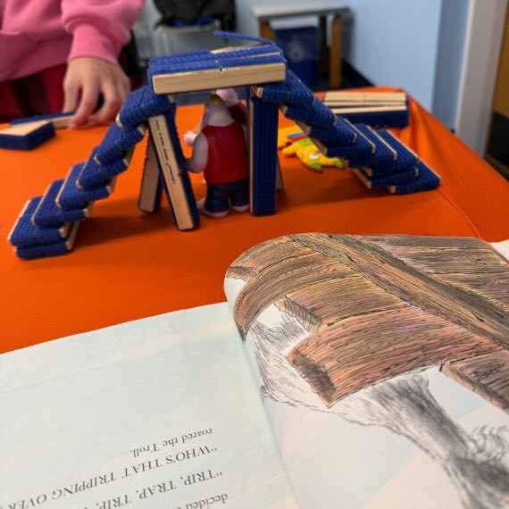 An open book with a small structure made of blocks behind it