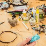 Assorted craft items on a table as a hand holds twine.