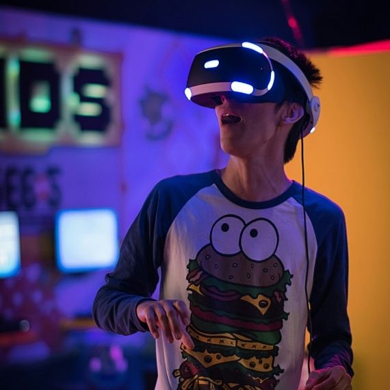 Young man wearing VR goggles looks excited.