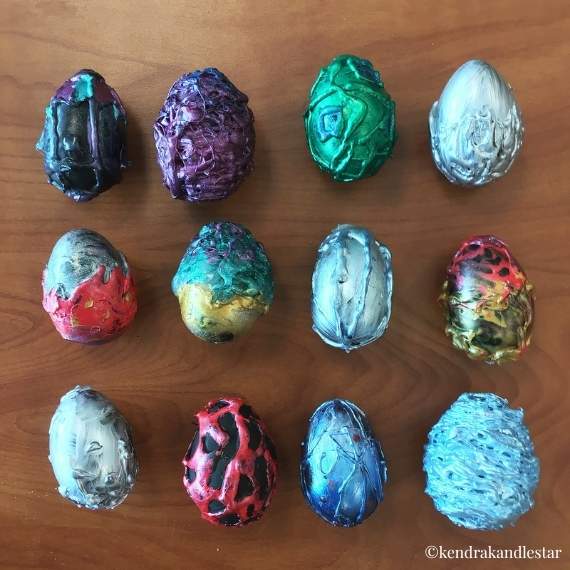 Multiple colourful eggs decorated with hot glue and painted over.