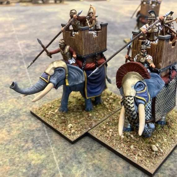 Miniature figures of soldiers on elephants on a table.