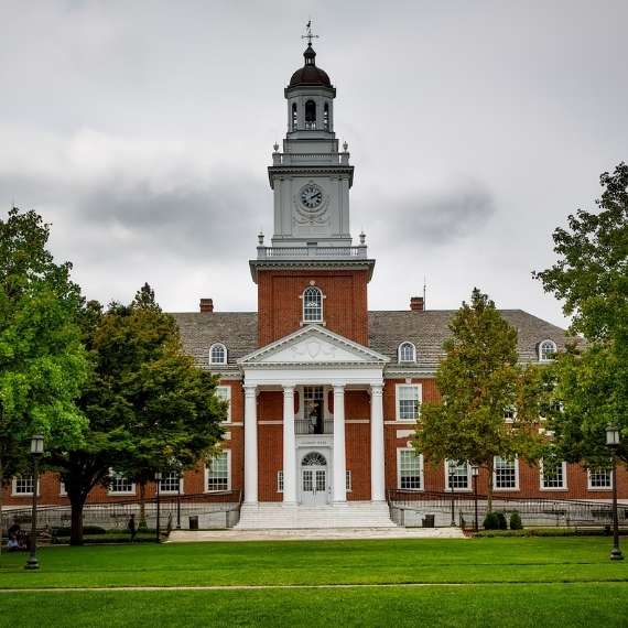 A red brick building with a clock tower and grass lawn in front of it