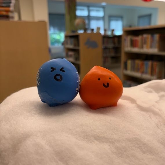 One blue ball made of mochi and one orange ball made of mochi with faces drawn on.