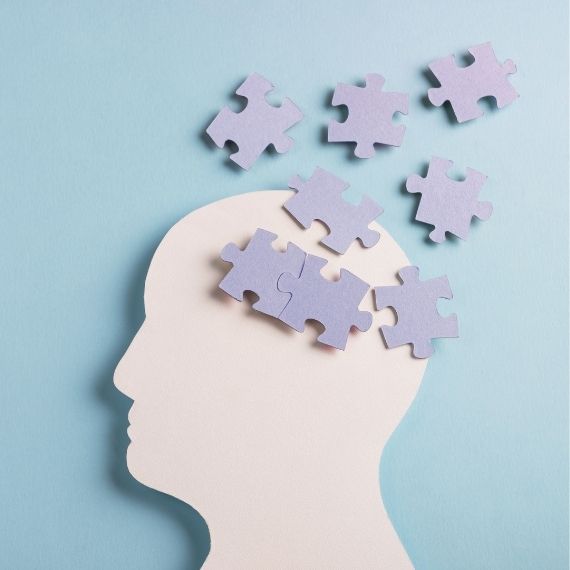 A paper cut out of a person's head with puzzle pieces