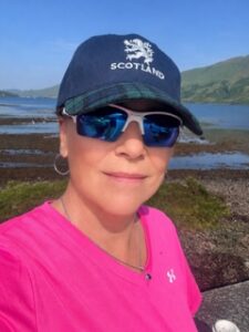 Woman in pink shirt, sunglasses, and navy baseball cap