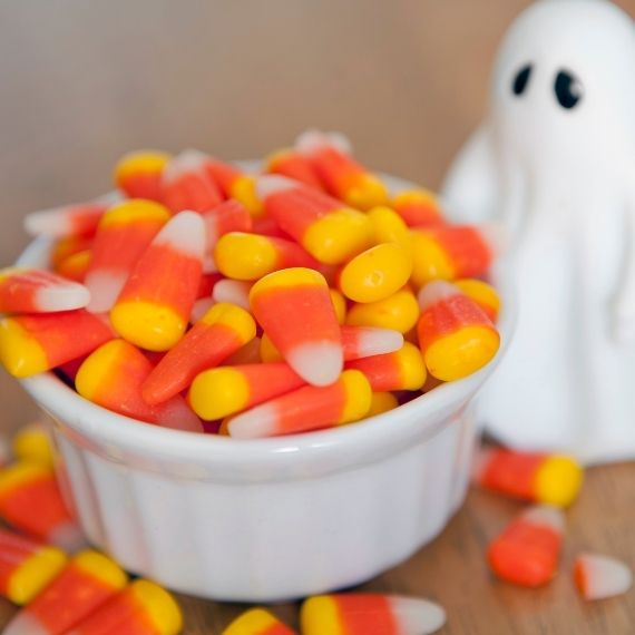 Bowl of candy corn next to a figurine of a ghost