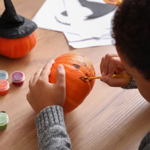 Child painting a small pumpkin
