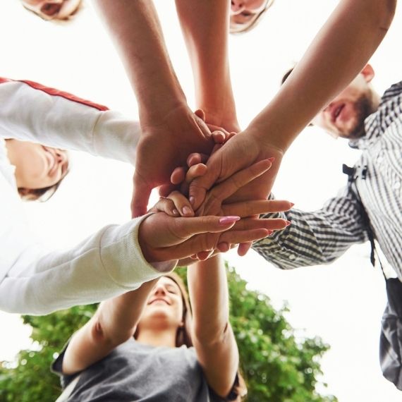 Looking from below at people putting their hands together